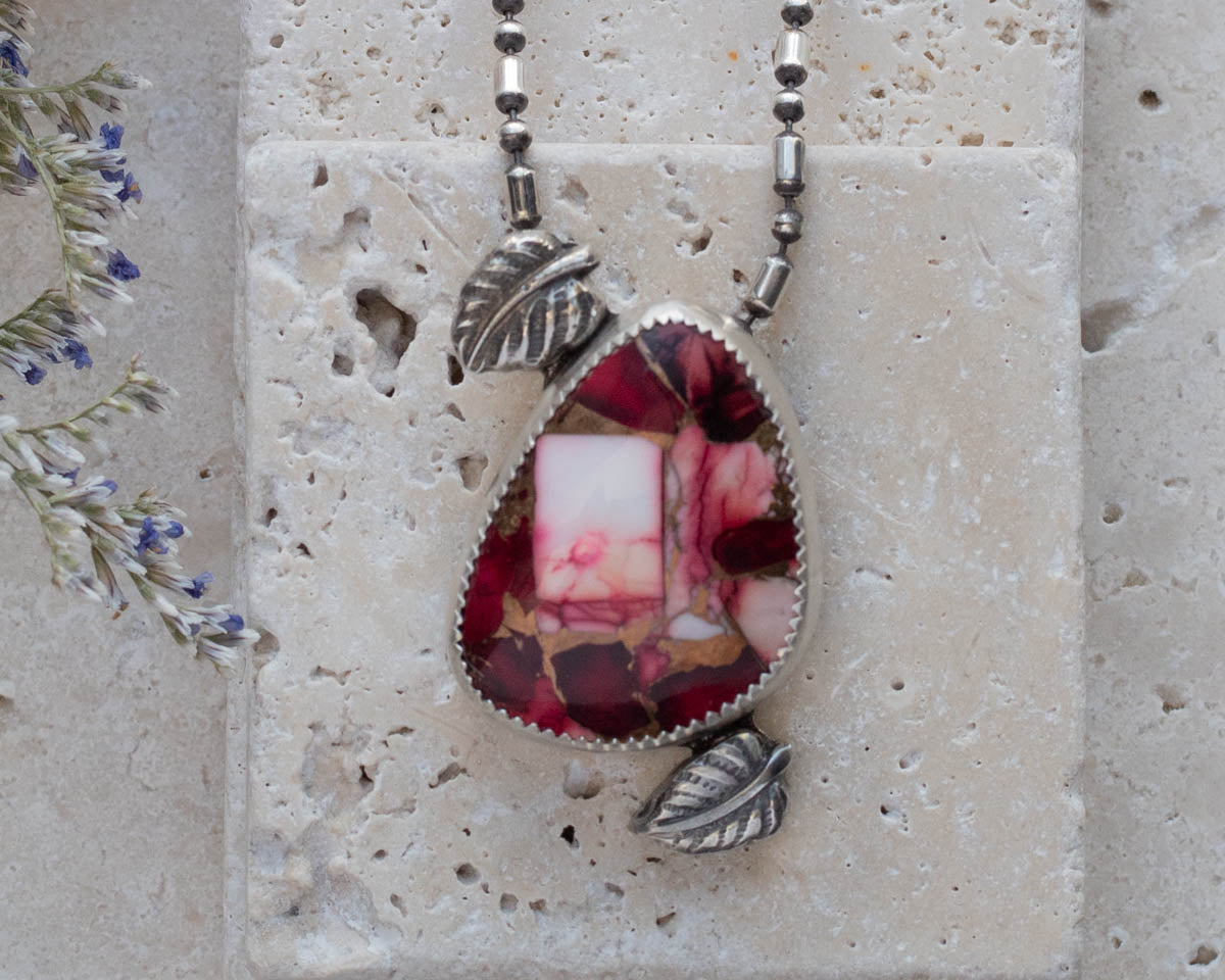 Handmade sterling silver pendant necklace featuring a red and pink dahlia jasper stone with leaf accents, set on a beaded oxidized chain for a nature-inspired artisan look.