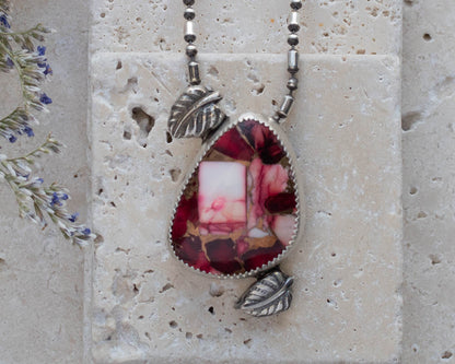 Handmade sterling silver pendant necklace featuring a red and pink dahlia jasper stone with leaf accents, set on a beaded oxidized chain for a nature-inspired artisan look.
