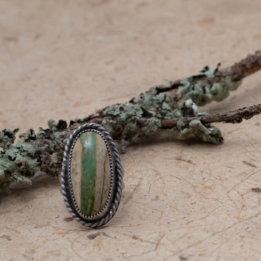 Royston Ribbon turquoise on bark with lichen covered branch in the background