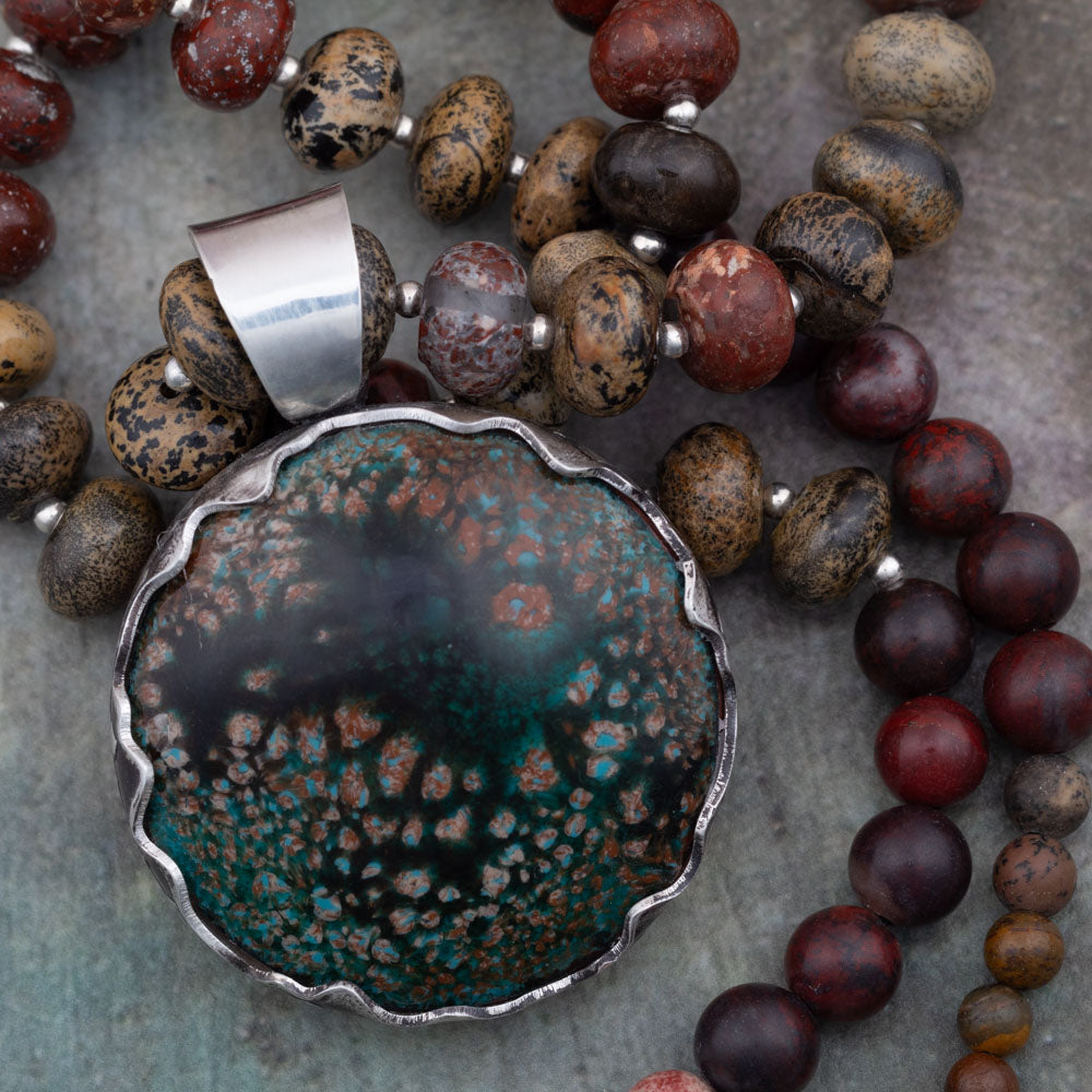 Rustic enamel and jasper beaded necklace featuring a scalloped sterling silver bezel setting and earthy tones of mossy green, brick red, and charcoal black