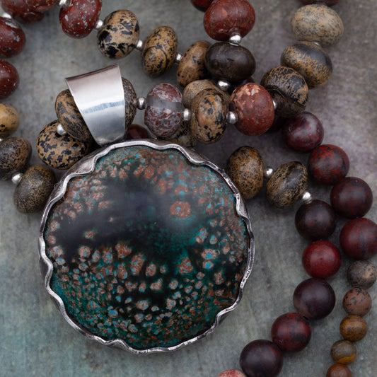 Rustic enamel and jasper beaded necklace featuring a scalloped sterling silver bezel setting and earthy tones of mossy green, brick red, and charcoal black