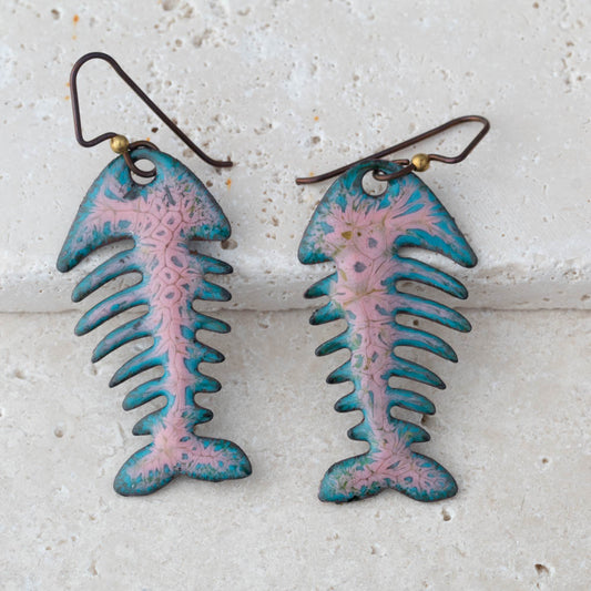 Pair of fish-shaped earrings with pink and blue design on a textured white background