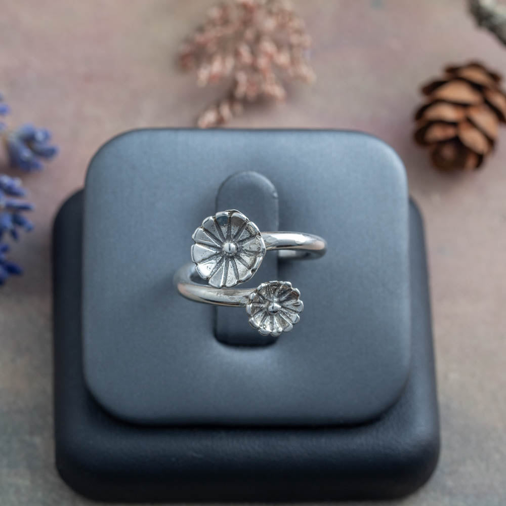 Silver floral ring on a black stand with a soft background