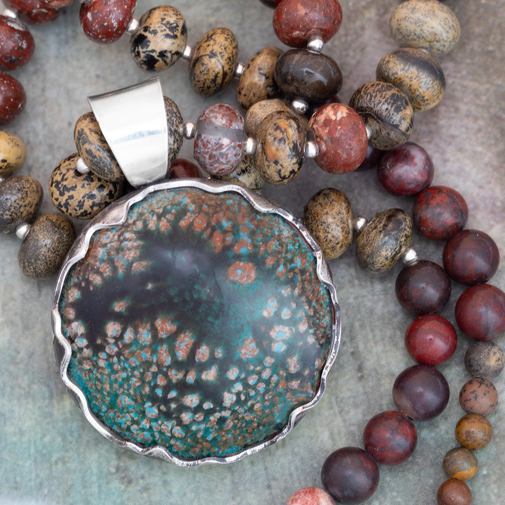 Rustic enamel and jasper beaded necklace featuring a scalloped sterling silver bezel setting and earthy tones of mossy green, brick red, and charcoal black