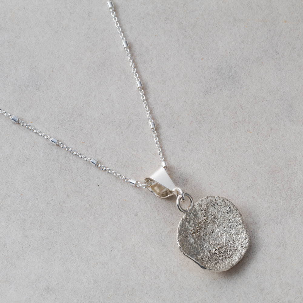 Fused silver dust necklace with organic lichen-like texture and sterling silver setting, handmade in Vermont by Divella Designs.