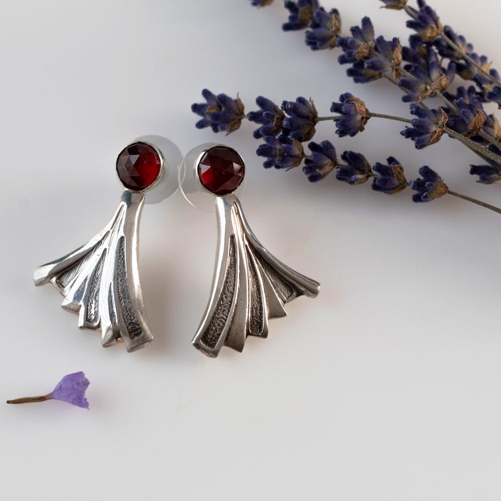 Garnet post earrings with fine silver settings, sterling silver posts, and 1 5/8 inch sculptural silver drops, handmade by Divella Designs in Vermont.