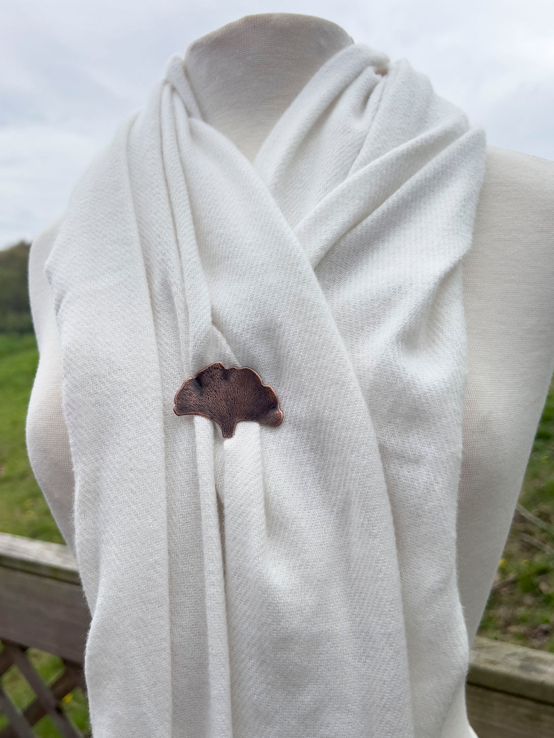 Handcrafted copper ginkgo leaf brooch with textured detail and organic fan shape, featuring nature-inspired botanical design and warm earthy patina. PIctured on a wool shawl.