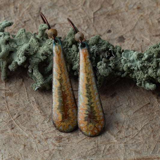 lichen enamel teardrop earrings in green gold and copper tones on natural lichen background handmade in Vermont