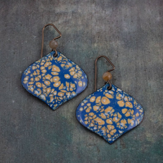 Handmade enamel earrings in deep blue with golden yellow petal pattern and niobium ear wires. Artisan jewelry with a nature-inspired organic texture.