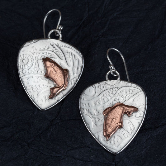 Handcrafted mixed metal earrings featuring copper jumping bass fish on textured fine silver backdrops with nature-inspired patterns – Gone Fishin’ earrings by Divella Designs, displayed on black background.