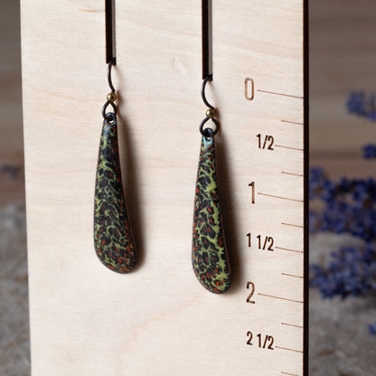 Green enamel teardrop earrings with dark organic texture, rusty orange details, and niobium ear wires.