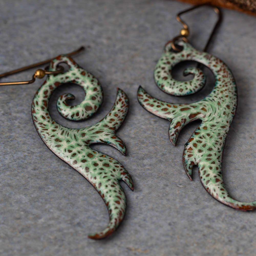 Pair of green and brown patterned earrings on a gray surface