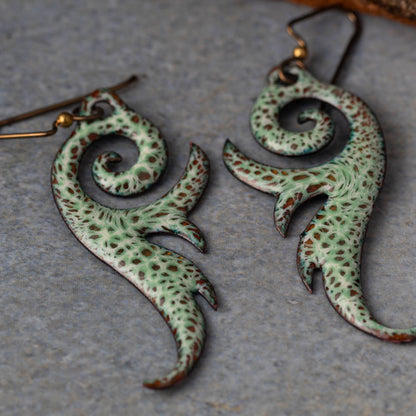 Pair of green and brown patterned earrings on a gray surface