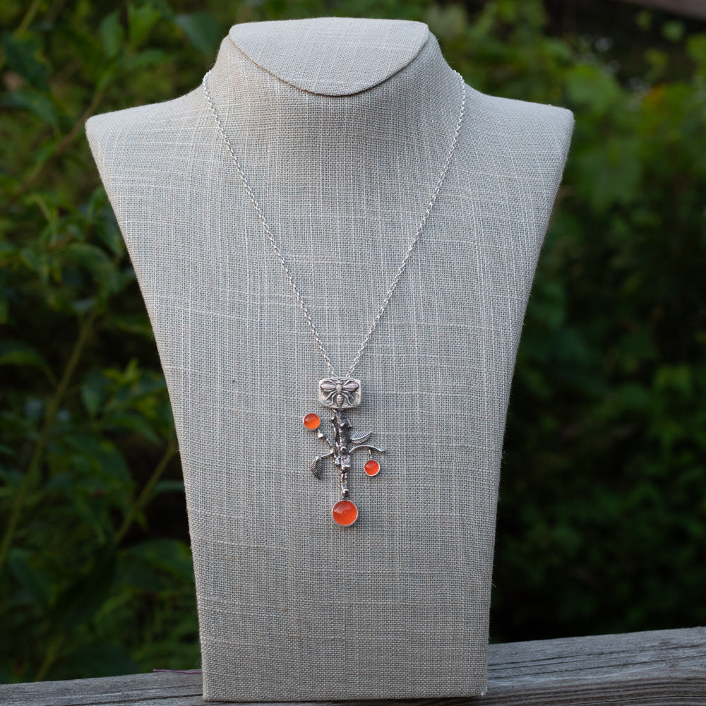 One-of-a-kind sterling silver branch pendant necklace with bee detail and bright carnelian stones displayed on a mannequin
