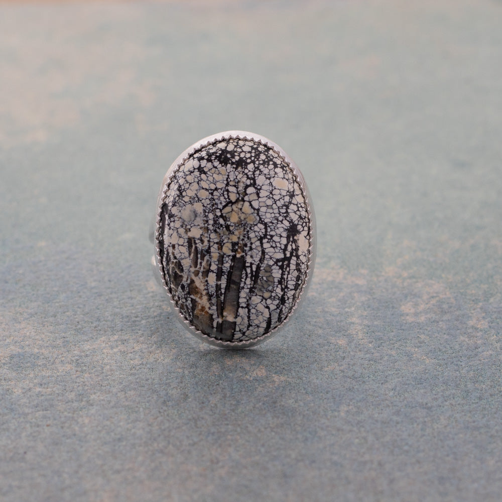 Sterling silver statement ring with an oval Ivory Creek Variscite stone in ivory, black, charcoal, and golden patterns.