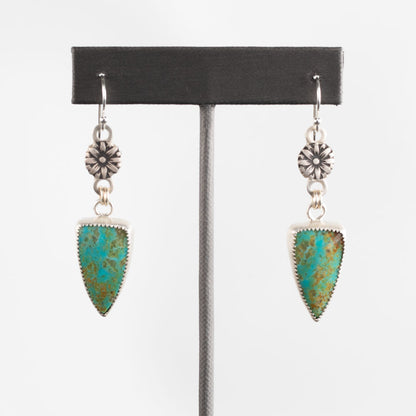 Sterling silver dangle earrings with shield-shaped turquoise stones and stamped floral accents, handcrafted Southwestern-style jewelry by Divella Designs – displayed on white background.