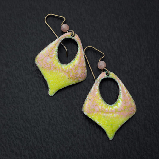Artisan enamel earrings in pastel pink and vibrant yellow with an organic speckled texture, featuring a diamond-shaped cutout design and niobium ear wires with soft pink stone bead accents.