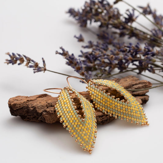 Handwoven yellow and green beaded earrings in a delicate leaf shape, featuring seed beads and metallic accents, handmade by Divella Designs.