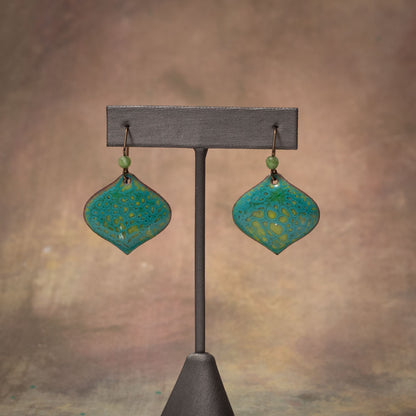 Handmade enamel earrings in teal and chartreuse with organic lichen-inspired patterns on copper and niobium ear wires.