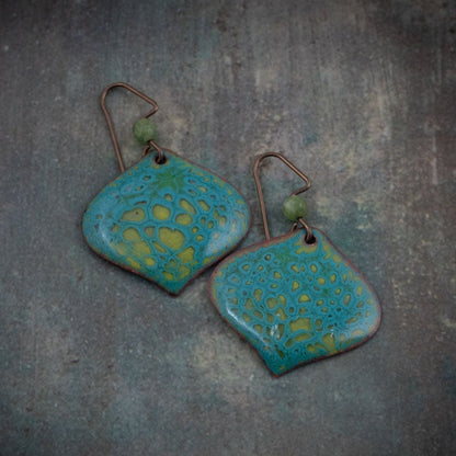 Handmade enamel earrings in teal and chartreuse with organic lichen-inspired patterns on copper and niobium ear wires.