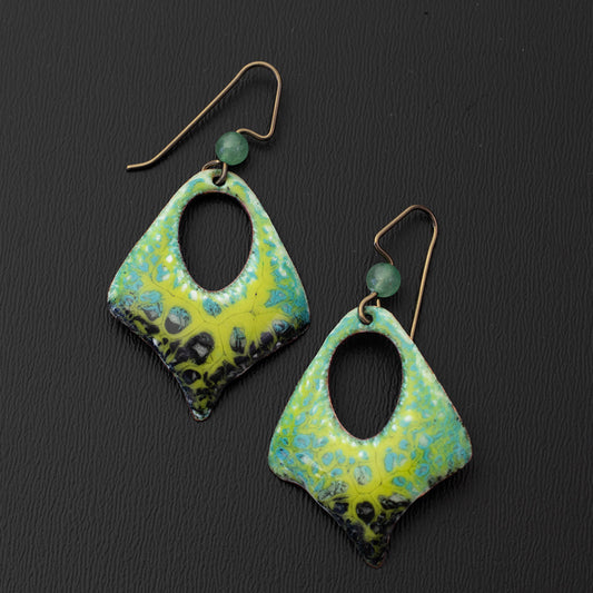 Handcrafted green and black enamel earrings with a diamond-shaped cutout design, textured lichen pattern, and niobium ear wires with green gemstone accents. Nature-inspired artisan jewelry.