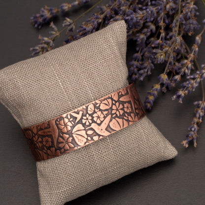 Etched copper cuff bracelet featuring a maple leaf pattern, displayed on a jewelry cushion with dried lavender on a dark background