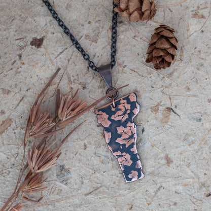 Handmade copper Vermont state pendant necklace with embossed maple leaf pattern and oxidized finish, featuring nature-inspired rustic design on patinated chain.