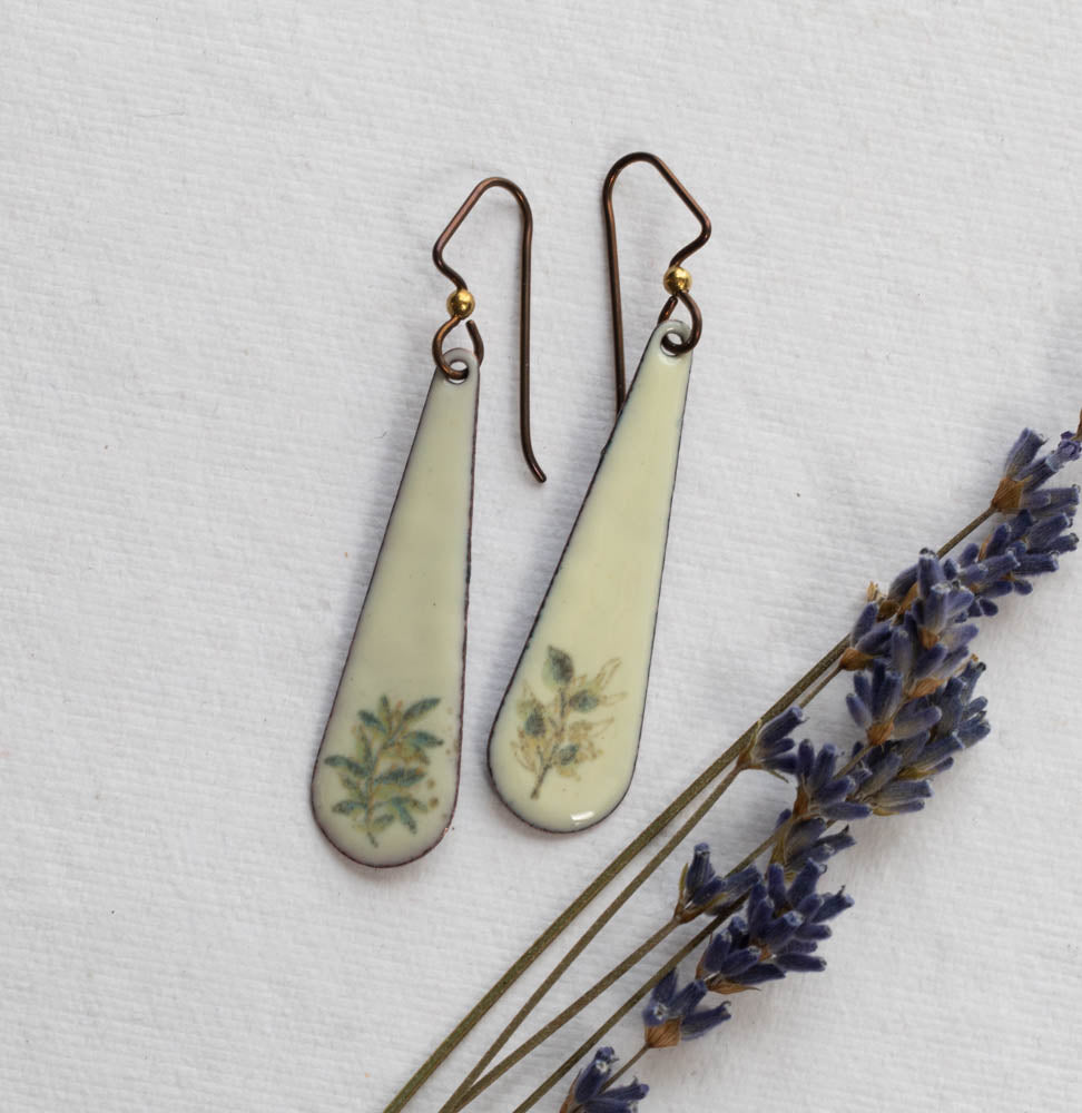 Teardrop-shaped earrings with floral designs on a white background with lavender.