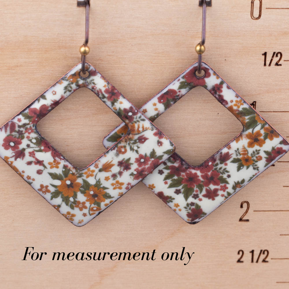 Floral patterned earrings on a wooden ruler for size reference