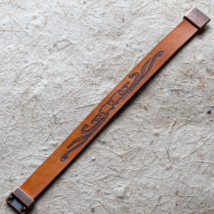 Brown leather cuff with decorative metal buckle on a textured surface