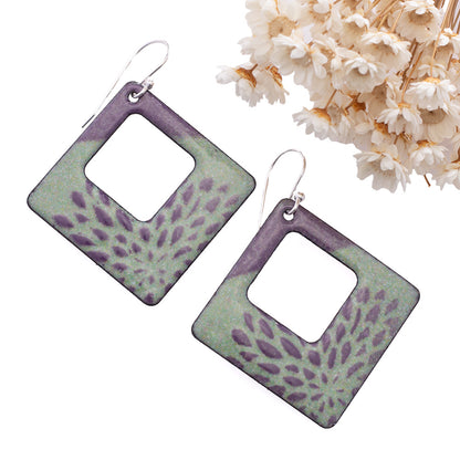 Handmade square enamel earrings in pastel mint green and purple floral design, open center with sterling silver ear wires – artisan jewelry by Divella Designs, styled with dried white flowers.