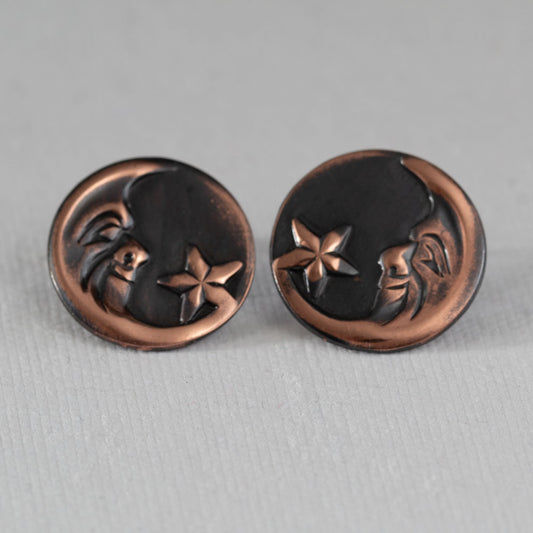 Oxidized copper post earrings featuring a crescent moon and star design – celestial jewelry with embossed face motif on dark patina background, artisan handcrafted style.
