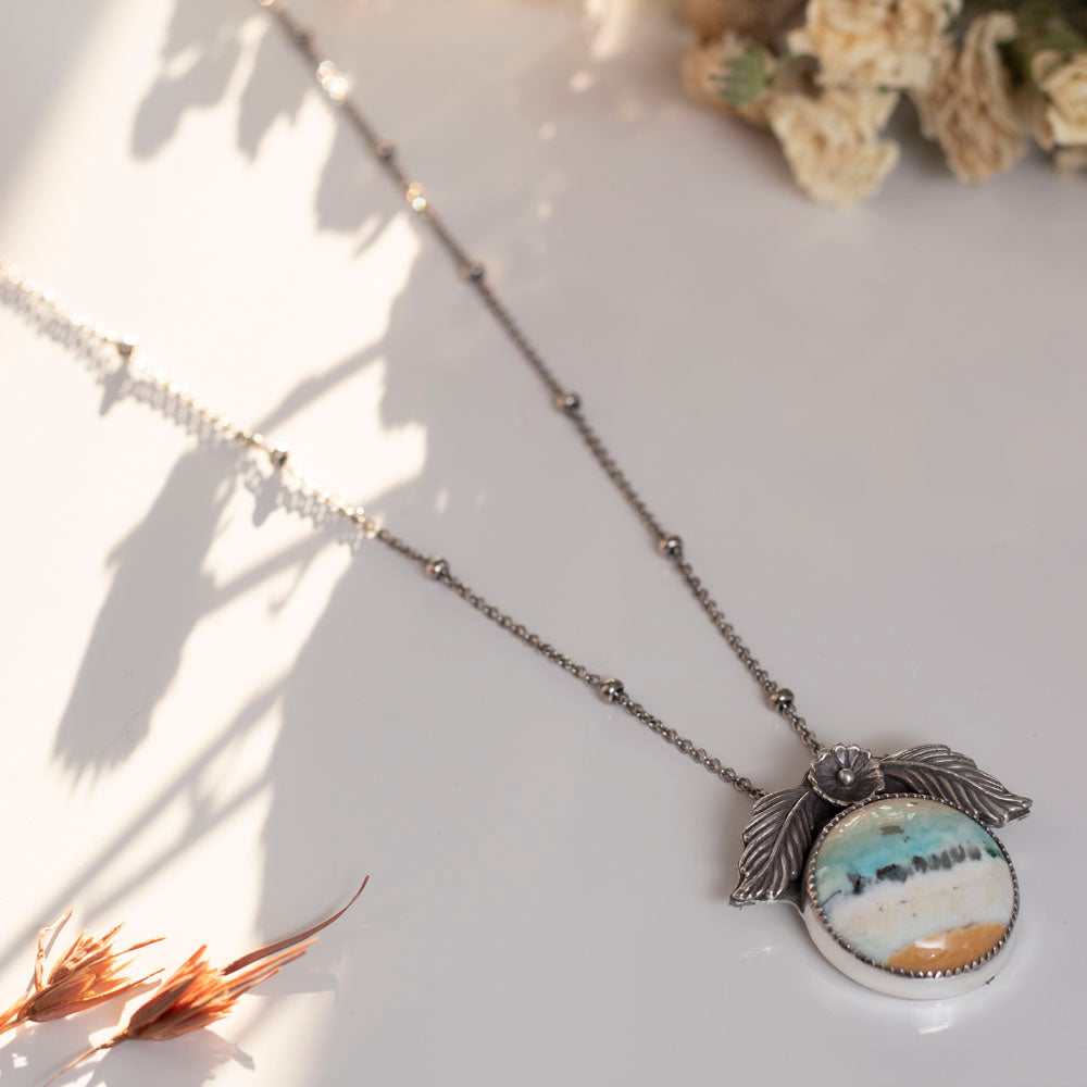 Handmade sterling silver necklace with opalized petrified wood and floral accents.
