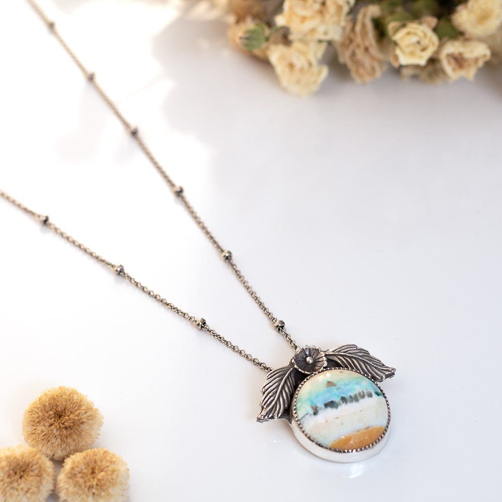 Handmade sterling silver necklace with opalized petrified wood and floral accents.