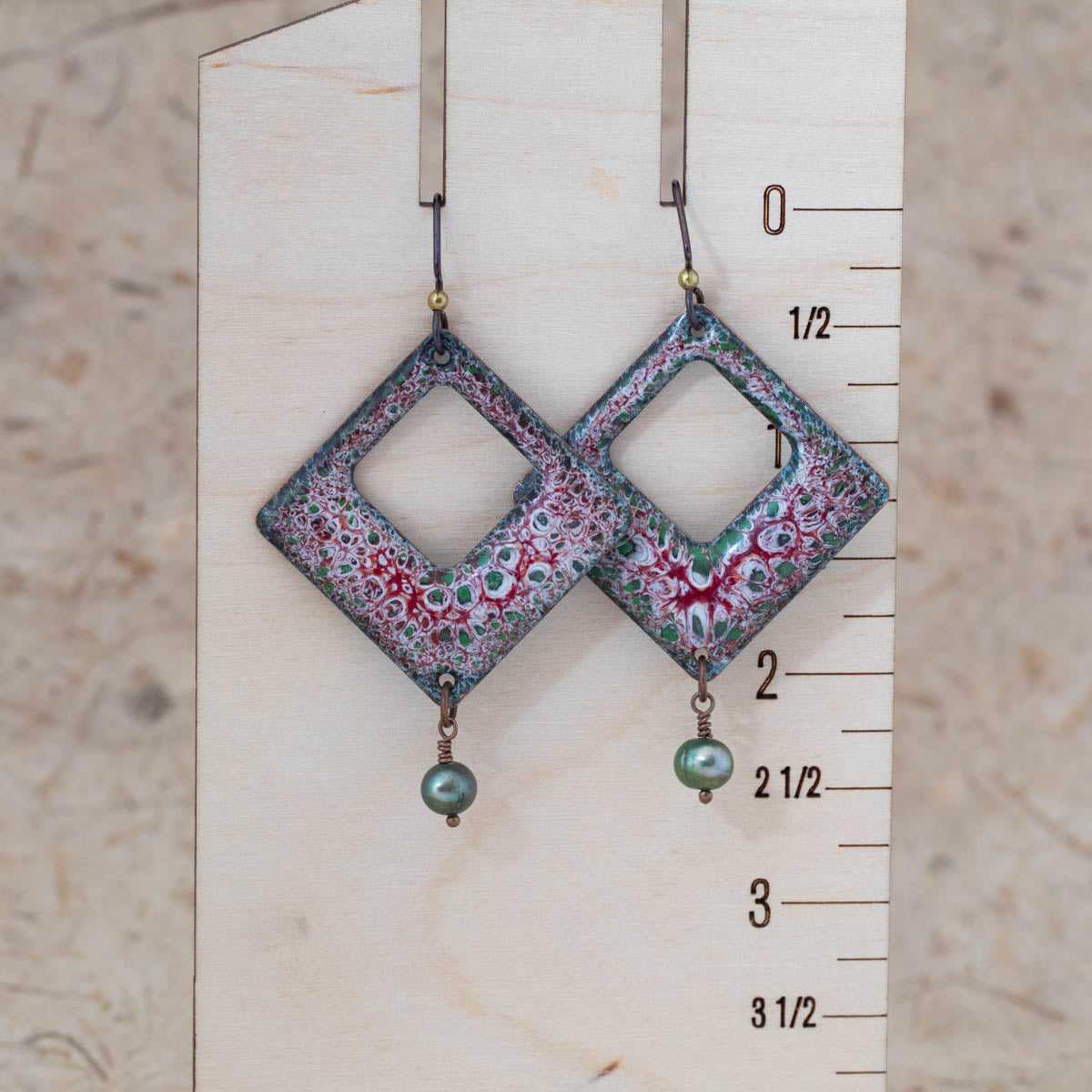 Red and green enamel pearl openwork earrings shown for scale with open center design and freshwater pearl drops.