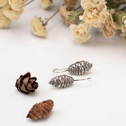 Sterling silver pine cone dangle earrings with nature-inspired design, handmade woodland jewelry.