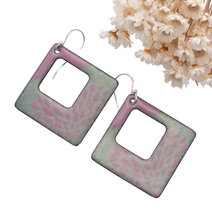 Handmade square enamel earrings in pastel mint green and pink floral design, open center with sterling silver ear wires – artisan jewelry by Divella Designs, styled with dried white flowers.