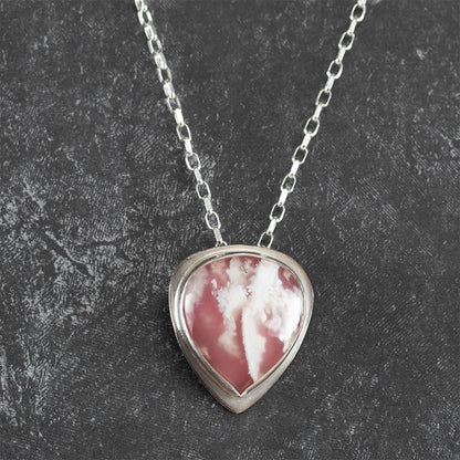 Sterling silver necklace featuring a teardrop-shaped pink and white plume agate stone, bezel set on a textured chain – handcrafted petal-inspired design by Divella Designs.