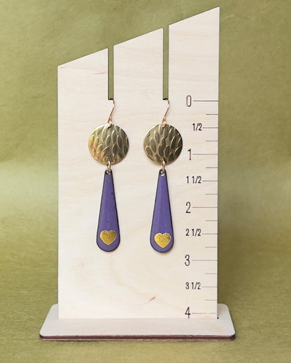 Pair of earrings on a measurement card against a green background