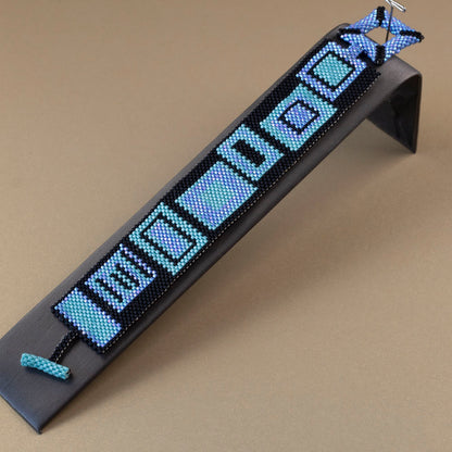 Handwoven beaded cuff bracelet with colorful geometric pattern on black background, fits 7 inch wrist