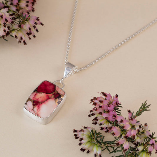 Handcrafted sterling silver pendant necklace with rectangular red and pink dahlia jasper stone, set in a serrated bezel on a delicate chain for a bold floral-inspired look.