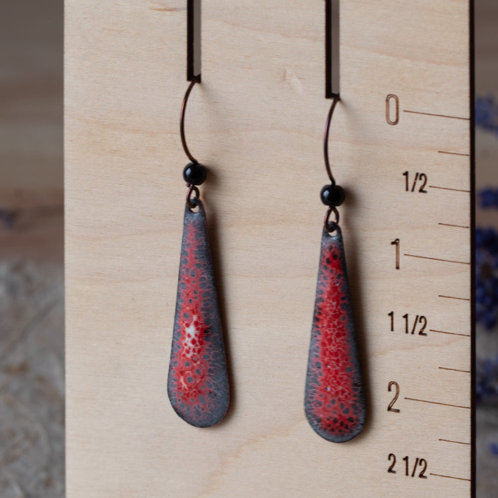 Red enamel teardrop earrings with dark speckled lace-like detail, black onyx beads, and niobium ear wires.
