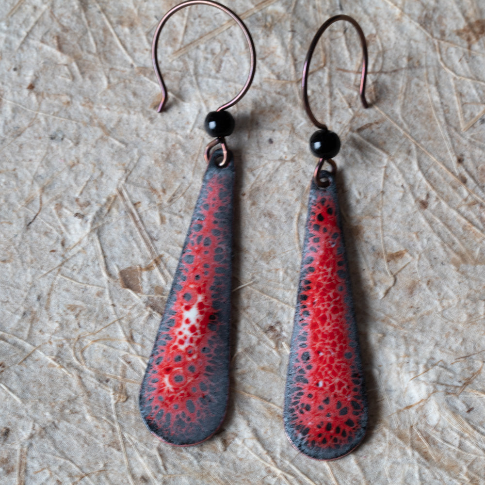 Red enamel teardrop earrings with dark speckled lace-like detail, black onyx beads, and niobium ear wires.