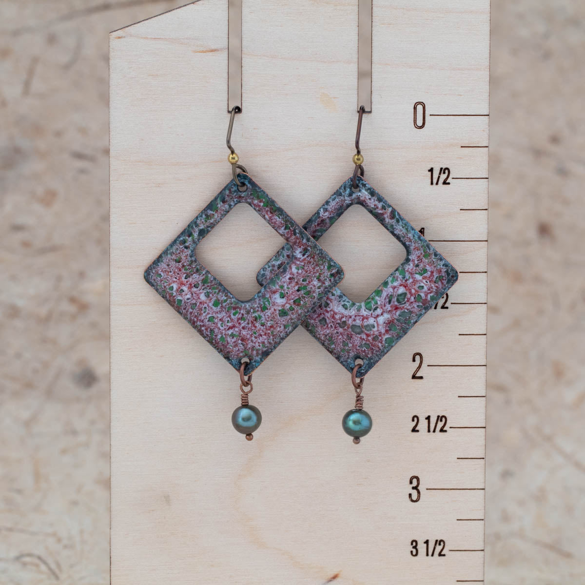 Red and green enamel openwork earrings shown for scale with airy center openings and freshwater pearl drops.