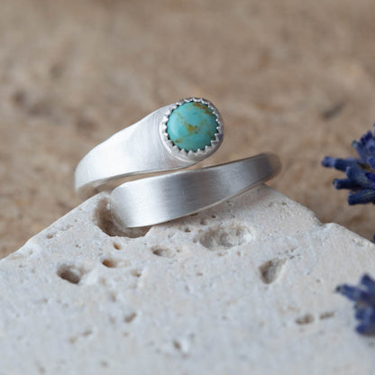 Adjustable sterling silver Kingman turquoise wrap ring photographed on a light stone surface