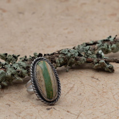 Royston Ribbon turquoise on bark with lichen covered branch in the background