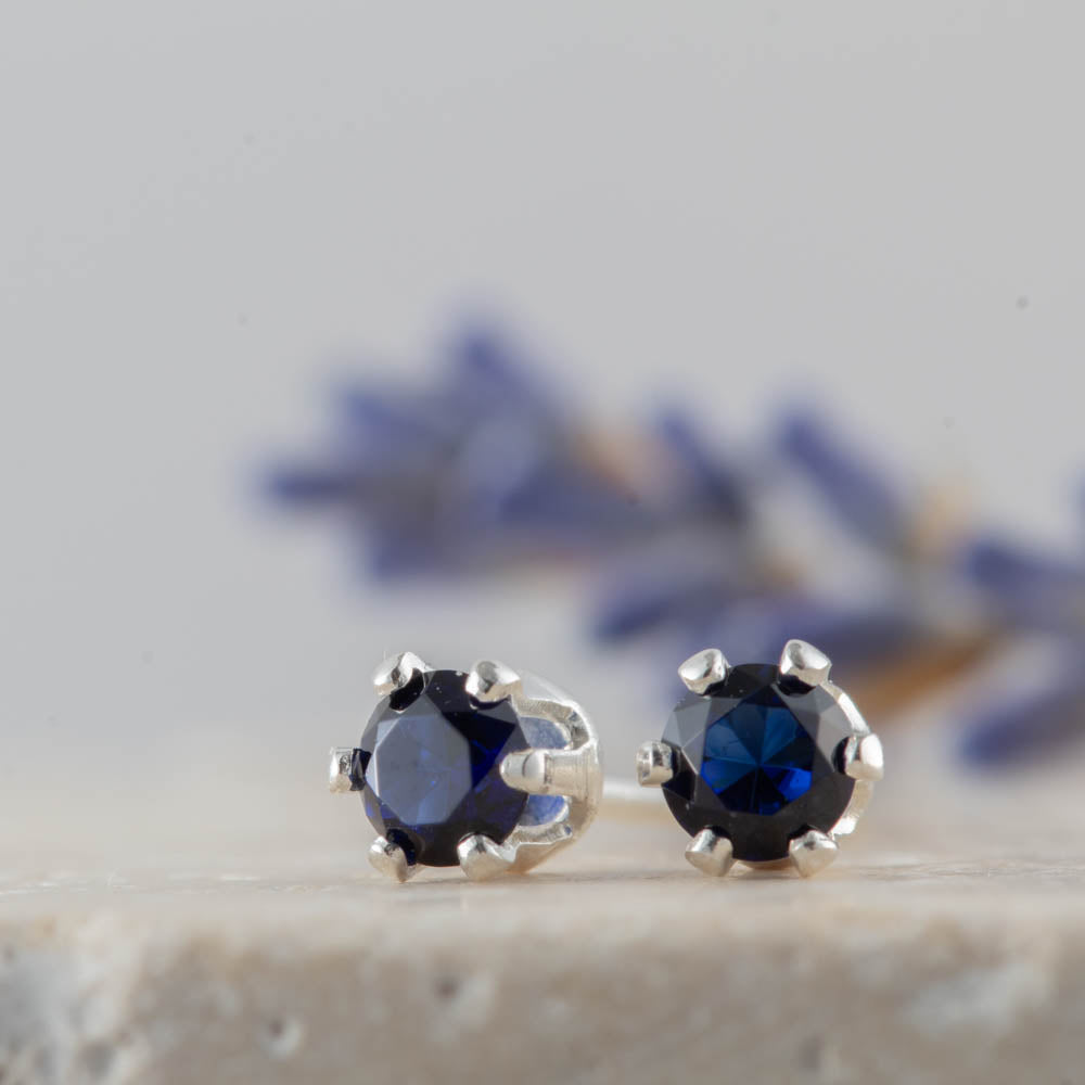 Pair of silver earrings with blue sapphire gemstones on a neutral background