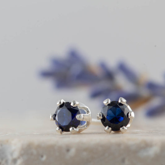 Pair of silver earrings with blue sapphire gemstones on a neutral background