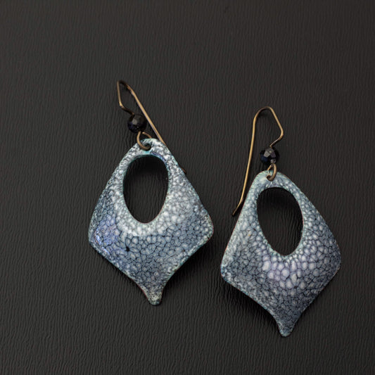 Diamond-shaped enamel earrings with a smoky blue and white speckled pattern, featuring an open teardrop center and niobium ear wires with black gemstone beads.