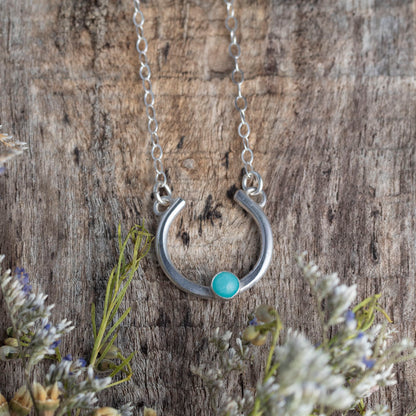 Silver necklace with a amazonite stone on a wooden background with plants